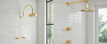 Unlacquered brass rain shower systems in a white tiled shower