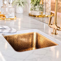 Unlacquered brass bar sink undermount in a white marble counter with a brass bar faucet