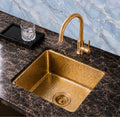 Hammered brass prep sink in a dark marble home bar with blue marble backsplash