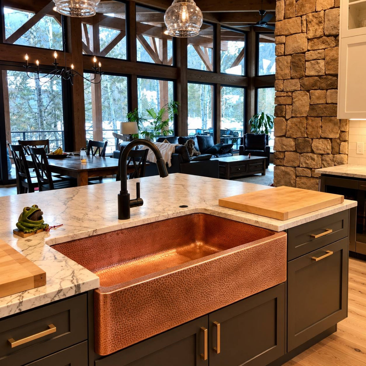 Hammered copper farmhouse kitchen sink installed in a log cabin kitchen island with marble counter