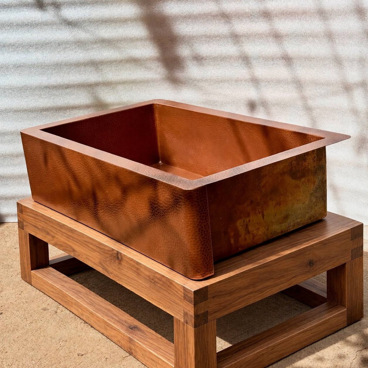 Hammered copper farmhouse kitchen sink on a wooden stand, Honey Copper finish